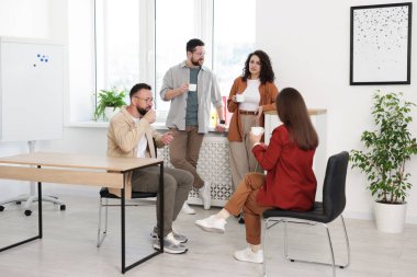 Ofiste kahve molası sırasında iş arkadaşları sohbet ediyor.