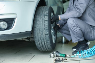 Tamirci araba servisinde lastik değiştiriyor, yakın plan.
