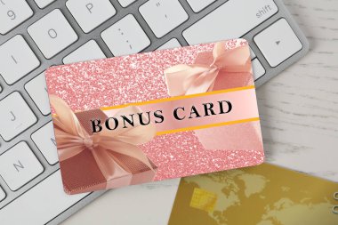 Beyaz ahşap masa üzerinde şık tasarım ve bilgisayar klavyeli bonus kart, üst görünüm