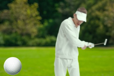 Golfçü, golf sopası ile topa vuruyor.