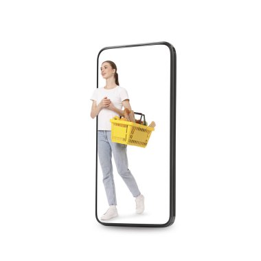 Alışveriş sepetli mutlu kadın beyaz arka planda cep telefonundan çıkıyor. Çevrimiçi sıralama