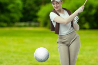 Golfçü, golf sopası ile topa vuruyor.