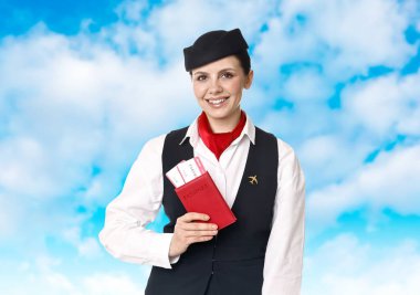 Gülümseyen hostes elinde bulutlu mavi gökyüzüne karşı pasaport tutuyor.