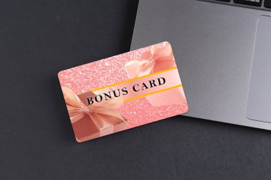 Gri masada şık tasarım ve dizüstü bilgisayarı olan bonus kart.