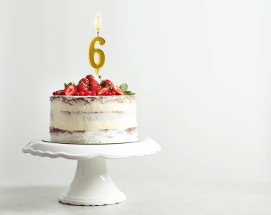 Beyaz arka planda 6 numara şeklinde yanan altın mumla nefis bir kek, mesaj için yer var. Doğum günü veya diğer özel durumlar