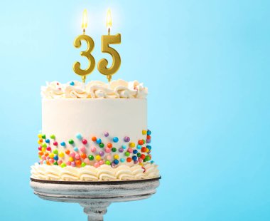 Açık mavi arkaplandaki mumların üzerine serpiştirilmiş pasta ve yanan numaralar, metin için yer. 35. Doğum günü veya diğer özel günler