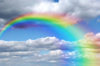 Mavi gökyüzünde parlak gökkuşağı güneşli bir günde bulutlarla