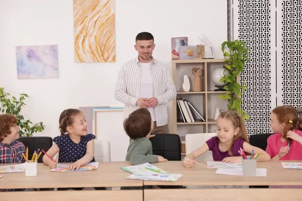 Çocuklara resim dersinde resim yapmayı öğreten bir adam.