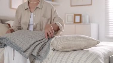 Yatakta battaniyeli ve yastıklı kadın, yakın plan. Ev tekstili