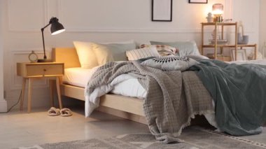 Odasında yumuşak çarşaflar ve battaniyeler olan rahat bir yatak, kamera sağa doğru hareket ediyor. Ev tekstili