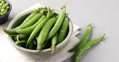 Gri masada taze taze taze bezelyeler, yakın plan. Kamera sola hareket ediyor