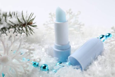 Nemlendirici dudak kremi, Noel dekorasyonu ve yapay kar üzerindeki köknar ağacı dalları, yakın plan. Kış bakımı