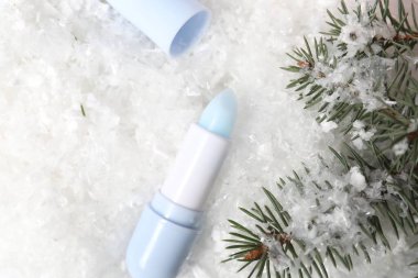 Nemlendirici dudak kremi ve yapay kar üzerinde köknar ağacı dalları. Kış bakımı