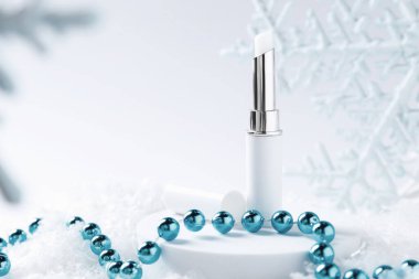 Nemlendirici dudak kremi ve yapay kar üzerine Noel süsü, yakın plan. Metin için boşluk