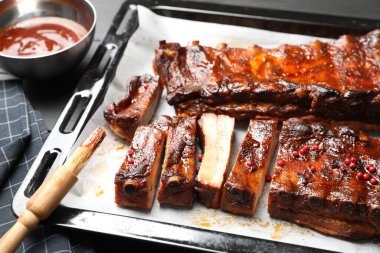 Lezzetli kaburgalar, sos ve fırça gri masada, yakın plan.