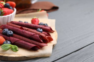 Lezzetli meyve dürümleri, çilekler, yaban mersinleri ve nane şekeri. Gri ahşap masa, yakın plan. Metin için boşluk