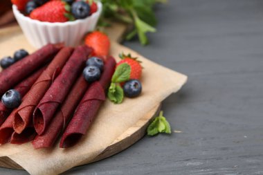 Lezzetli meyve dürümleri, çilekler, yaban mersinleri ve nane şekeri. Gri ahşap masa, yakın plan. Metin için boşluk