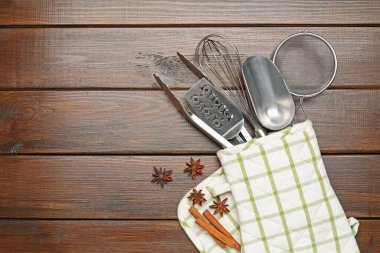 Farklı mutfak aletleri fırın eldiveni, tarçın ve ahşap masa üzerinde anason yıldızları, düz yatak. Metin için boşluk