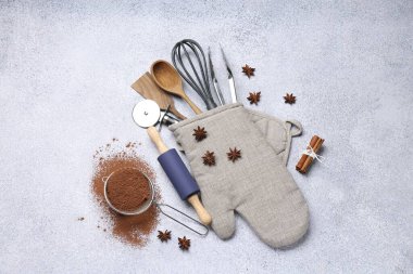 Farklı mutfak aletleri fırın eldiveni, kakao tozu, tarçın ve anason yıldızları ışık masasında, düz yatıyordu.