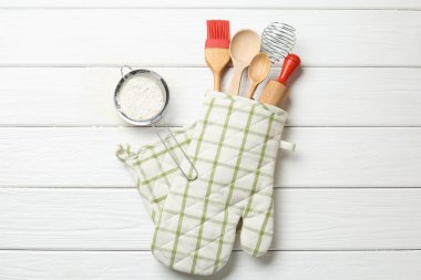 Farklı mutfak aletleri fırın eldiveni ve un beyaz ahşap masa, düz yatıyordu.