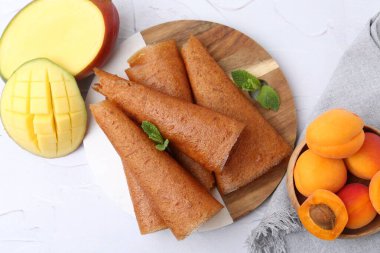 Lezzetli meyve dürümleri, nane, mango ve kayısılar beyaz masada, düz yatıyordu.