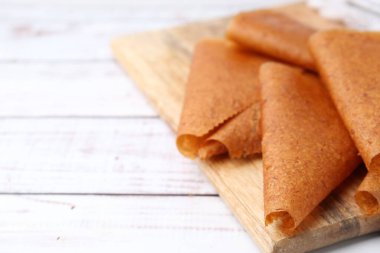 Lezzetli meyve derisi beyaz ahşap masada yuvarlanıyor, yakın plan. Metin için boşluk