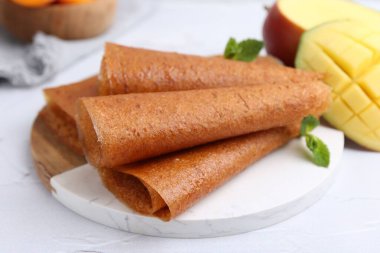 Lezzetli meyve dürümleri, nane ve mango beyaz masada, yakın plan.