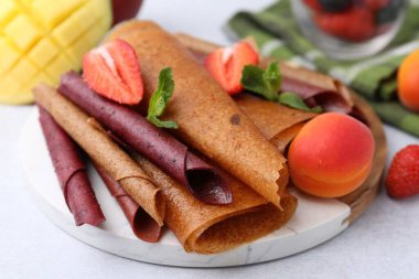 Lezzetli meyve dürümleri, nane, kayısı, mango ve çilek ışık masasında, yakın plan.