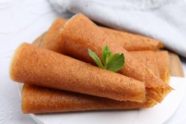 Lezzetli meyve dürümleri ve nane şekeri beyaz masada, yakın plan.