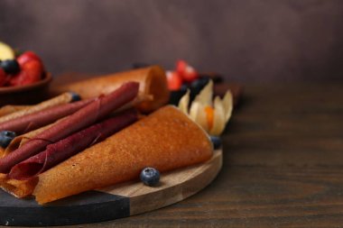 Lezzetli meyve dürümleri ve ahşap masada meyveler, yakın plan. Metin için boşluk