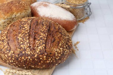 Taze ekmek somunları ve çiviler beyaz fayanslı masada, yakın plan.