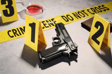 Adli tıp uzmanlığı. Açık gri arka planda delil, işaret ve polis bandı olan suç mahalli, yakın plan