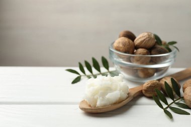 Doğal Shea yağı, fındık ve yapraklar beyaz ahşap masada, yakın plan. Metin için boşluk