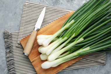 Taze taze yeşil soğanlar kesme tahtası ve bıçakla gri desenli masa, düz yatıyordu.