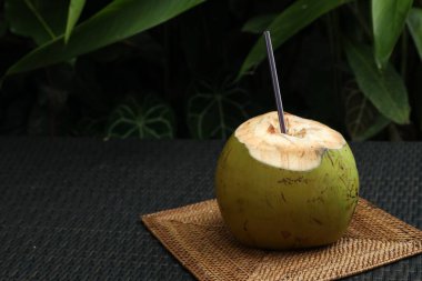 Yeşil hindistan cevizi, ferahlatıcı içecek ve hasır hasır masa üzerinde saman, yakın plan. Metin için boşluk