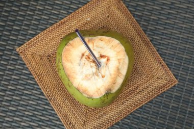 Yeşil hindistan cevizi, taze içecek ve hasır masa üzerinde saman, üst görünüm