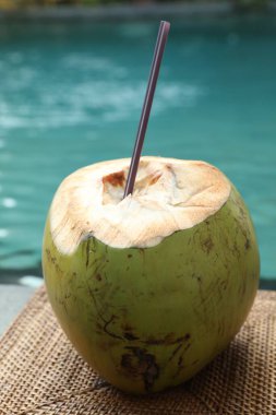 Yeşil hindistan cevizi, ferahlatıcı bir içecek ve hasır üzerinde hasır yüzme havuzu yakınında, yakın plan.