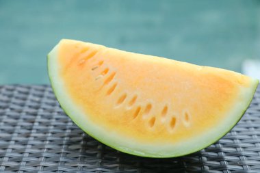 Açık havuz kenarında hasır masada lezzetli bir karpuz dilimi, yakın plan.