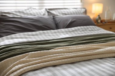 Odasında yumuşak çarşaflar ve battaniyeler olan rahat bir yatak, yakın plan. Ev tekstili