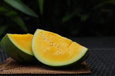 Hasır masada olgun sarı karpuz parçaları, yakın plan. Metin için boşluk