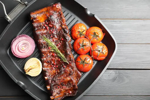 Biberiyeli domuz pirzolası, domates ve soğan. Gri ahşap masa, üst manzara.