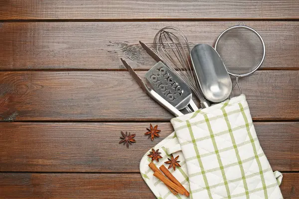 Farklı mutfak aletleri fırın eldiveni, tarçın ve ahşap masa üzerinde anason yıldızları, düz yatak. Metin için boşluk