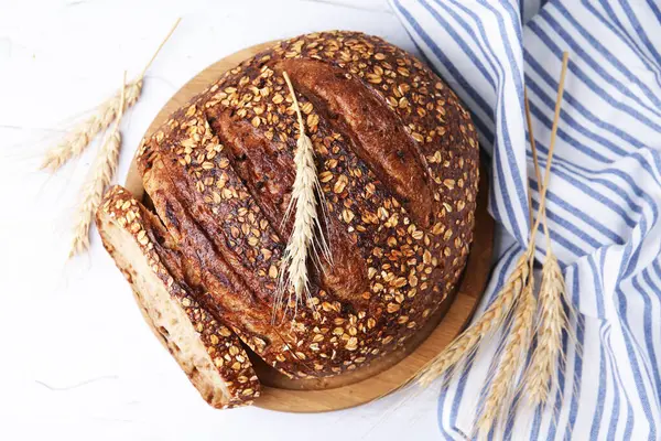 Taze pişmiş somun ekmek, yulaf lapası ve çivili, düz bir masa.