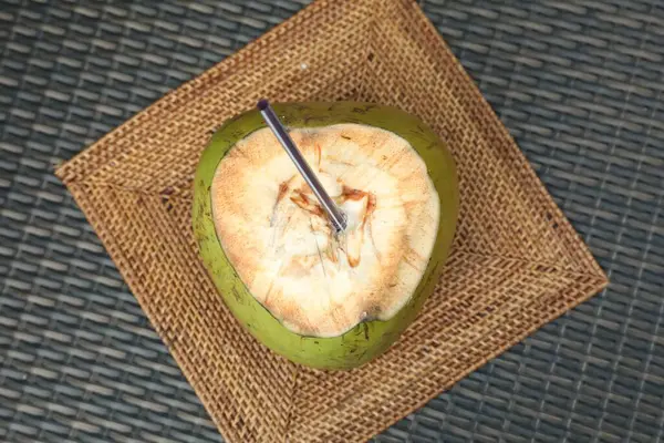 Yeşil hindistan cevizi, taze içecek ve hasır masa üzerinde saman, üst görünüm