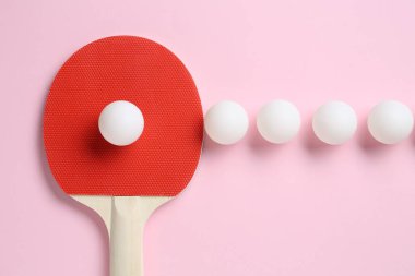 Masa tenisi raketi ve toplar pembe arka planda, düz yatıyordu.