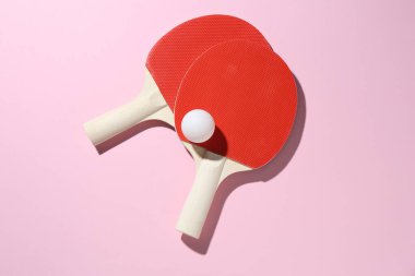 Ping pong raketleri ve pembe zemin üzerinde top, düz yatıyordu.