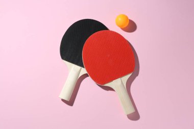 Ping pong raketleri ve pembe zemin üzerinde top, düz yatıyordu.