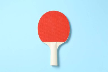 Açık mavi arka planda bir pinpon raketi, üst görünüm.