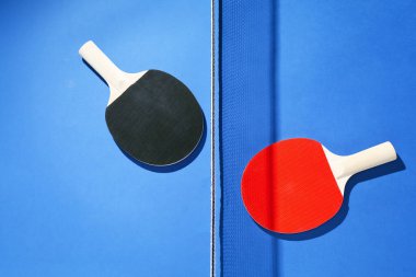 Masa tenisi raketleri ve mavi arka planda net, düz yatıyordu.