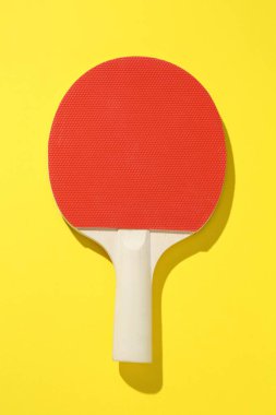 Sarı arka planda bir ping pong raketi, üst manzara.